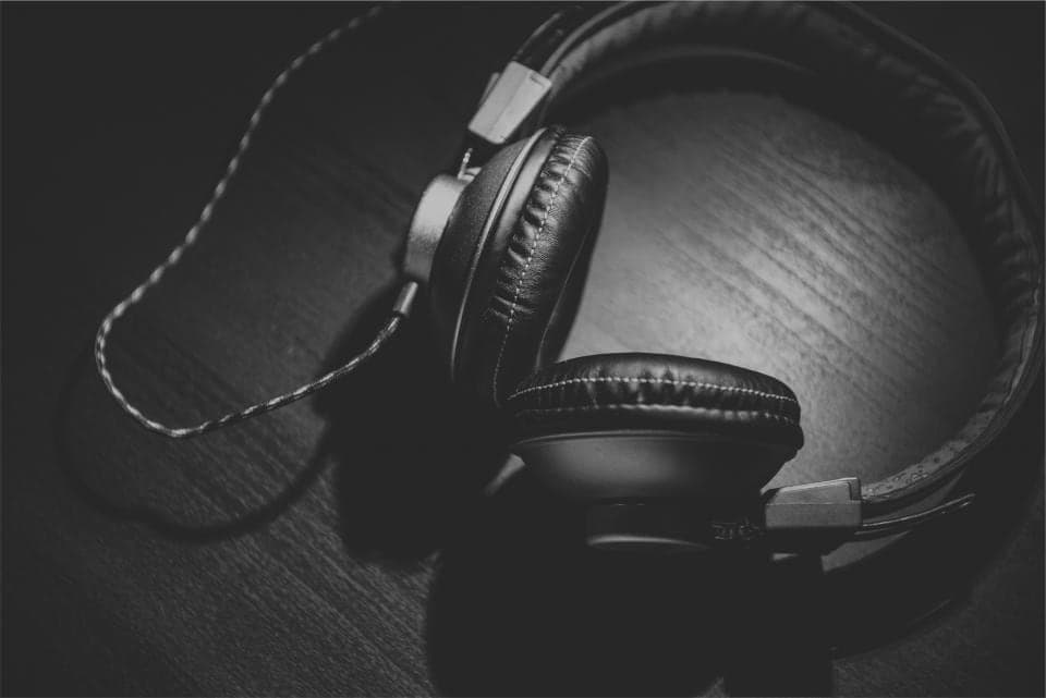 Headphone over-ear hitam tergeletak di atas meja kayu gelap